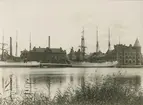 Skonare förtöjda vid kajen i Gustavsbergs hamn, med Gula byggningen i mitten och Huvudkontoret till höger.