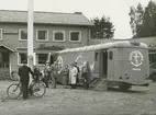 Exteriör. Gustavsbergsbussen parkerad utanför Folkets Hus och Forum. Sannolikt stad eller ort i Norrland.
Personer: okända