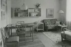 Interiörbild, vardagsrum. Sannolikt Grindstugärde från utställningen Så ska vi haÂ´t  med fyra möblerade lägenheter arrangerad av arkitekt Olof Thunström och Svenska Slöjdföreningen.