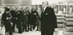 Interiör. Sannolikt invigning av Domusvaruhuset 1964 med föreningschefen Mattson i förgrunden.
Personer: I förgrunden med mikrofon: Gunnar Mattson. I fonden Harald Lindholm, Evert Andersson,  Axel Öhlund ombudsman för Fabriks avd 205 och övriga  bl a Linus Lindvall, Ville Westin, Ruben Edqvist och Einar Svensk