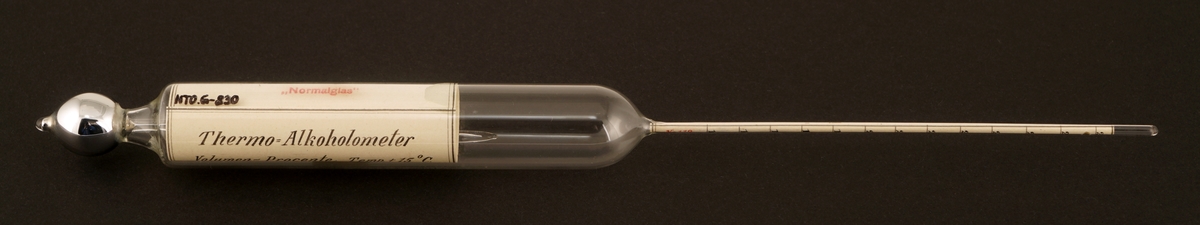 Alkoholmeter av glass  som ligger i et etui av papp