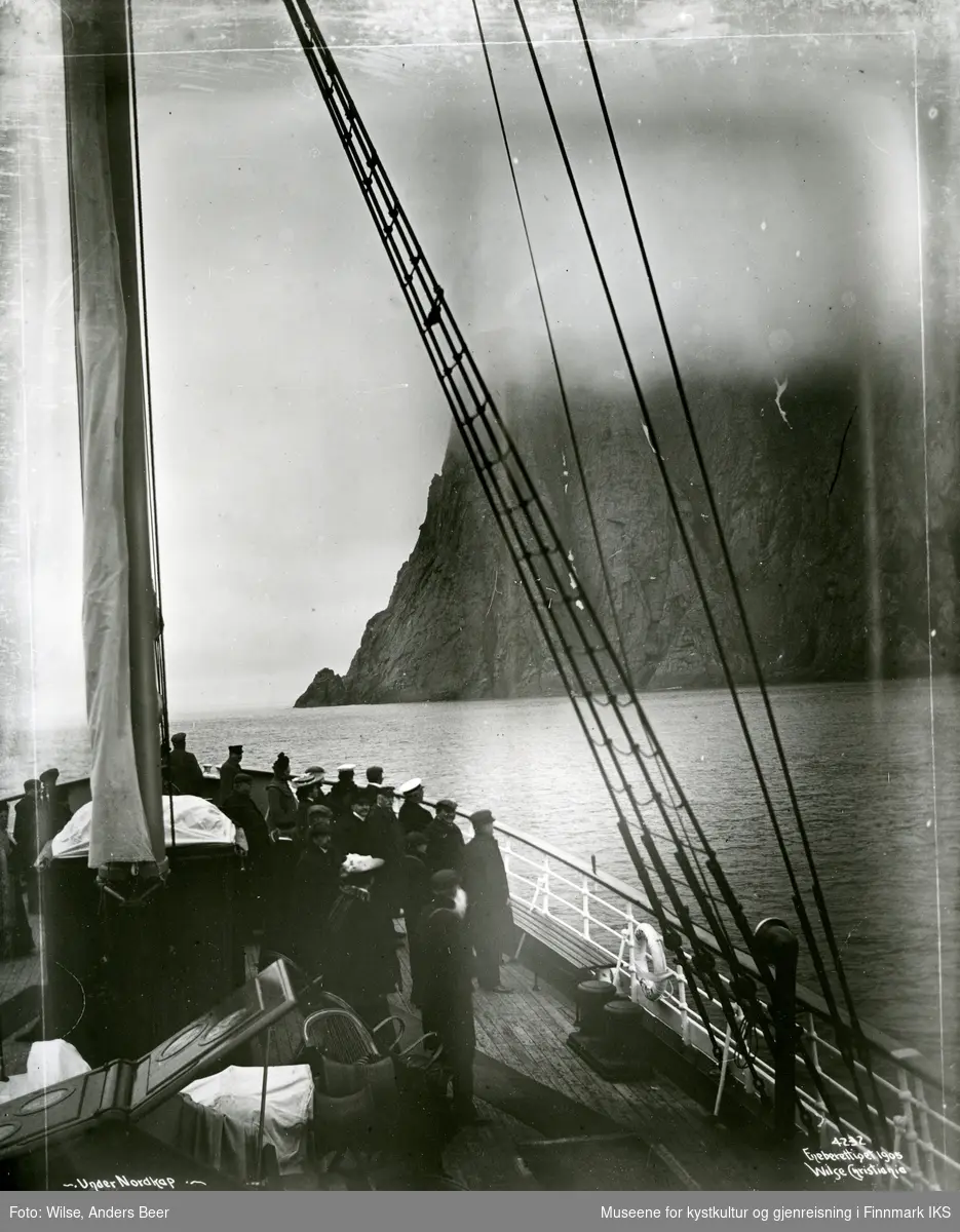 Turistskip utenfor Nordkappklippen. Platået forsvinner i tåke. 25.06. eller 23.07.1906. (Originalnegativet eies av Norsk Folkemuseum, W 04232)