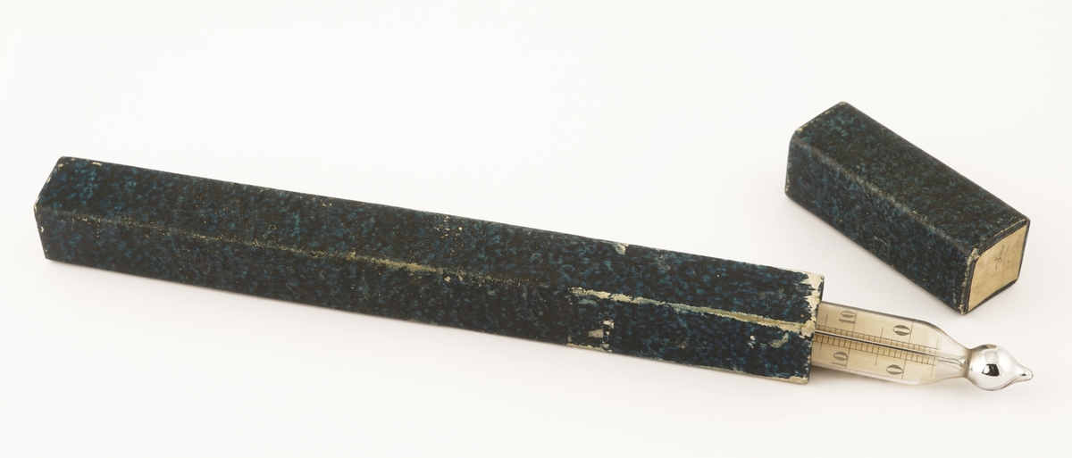 Termometer av glass  som ligger i et firkantet etui av formentlig papp.