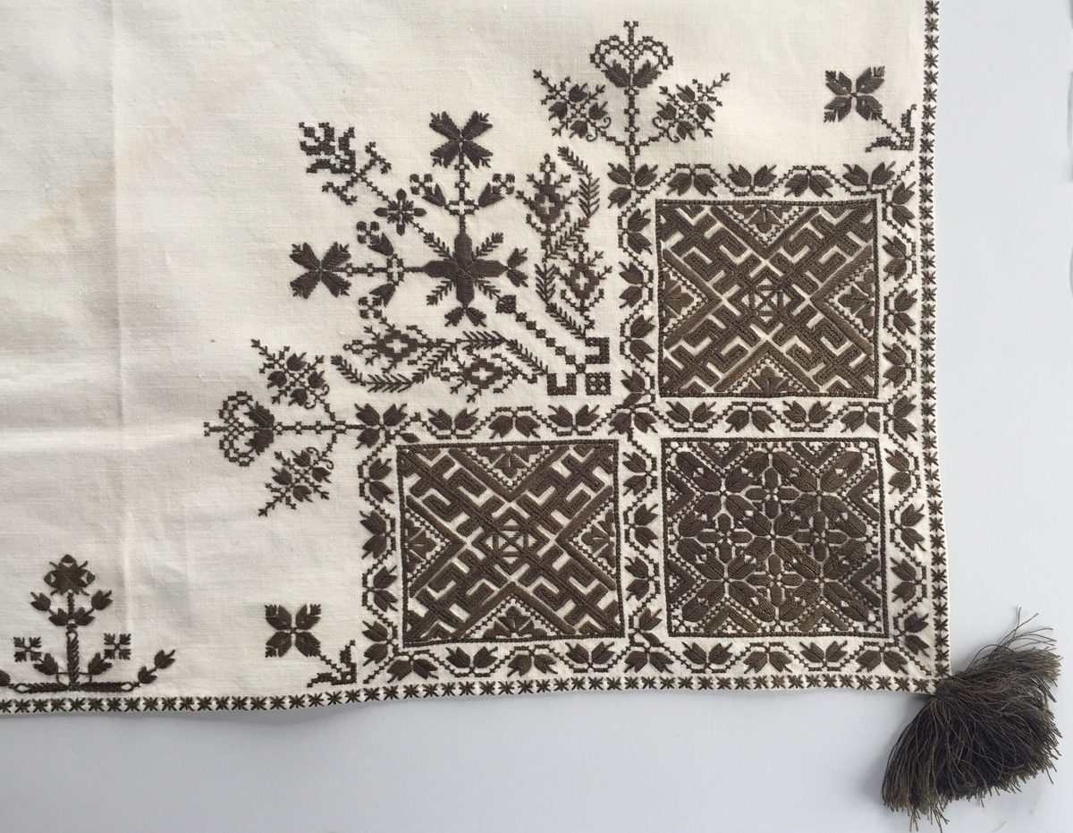 Blomsterinspirerat mönster i kvadrater i hörnen. Runt kvadraterna bård i blomstermotiv. Mellan kvadraterna på ryggsnibb och framsnibbar blomsterdekoration.  På ryggsnibben tre kvadrater och en dekorerad  majstångsspira. På varje framsnibb en kvadrat och en trekant.