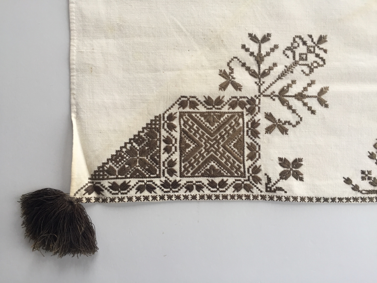 Blomsterinspirerat mönster i kvadrater i hörnen. Runt kvadraterna bård i blomstermotiv. Mellan kvadraterna på ryggsnibb och framsnibbar blomsterdekoration.  På ryggsnibben tre kvadrater och en dekorerad  majstångsspira. På varje framsnibb en kvadrat och en trekant.