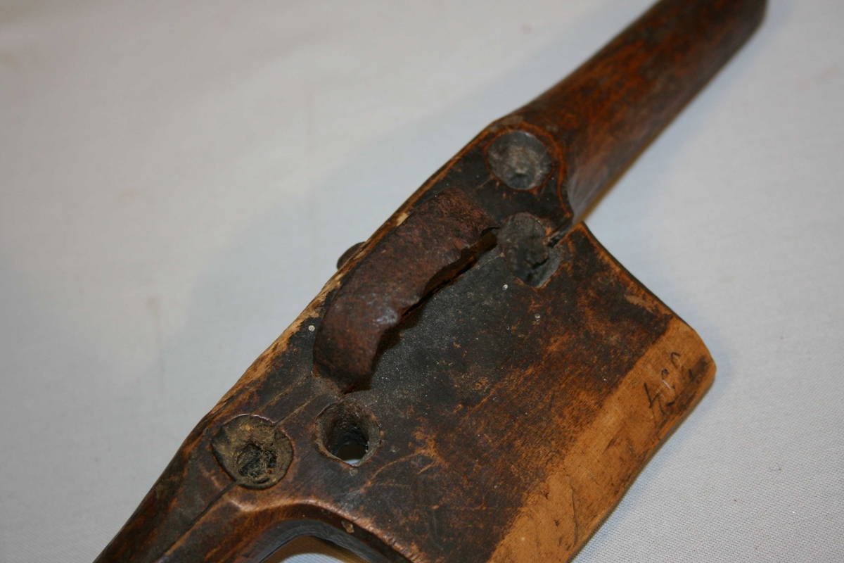 Trestykke med eit handtak i kvar ende, Eggjern  med profilar midt på. Pynta med profilar og border. Jernet rusta, treet sprekt.