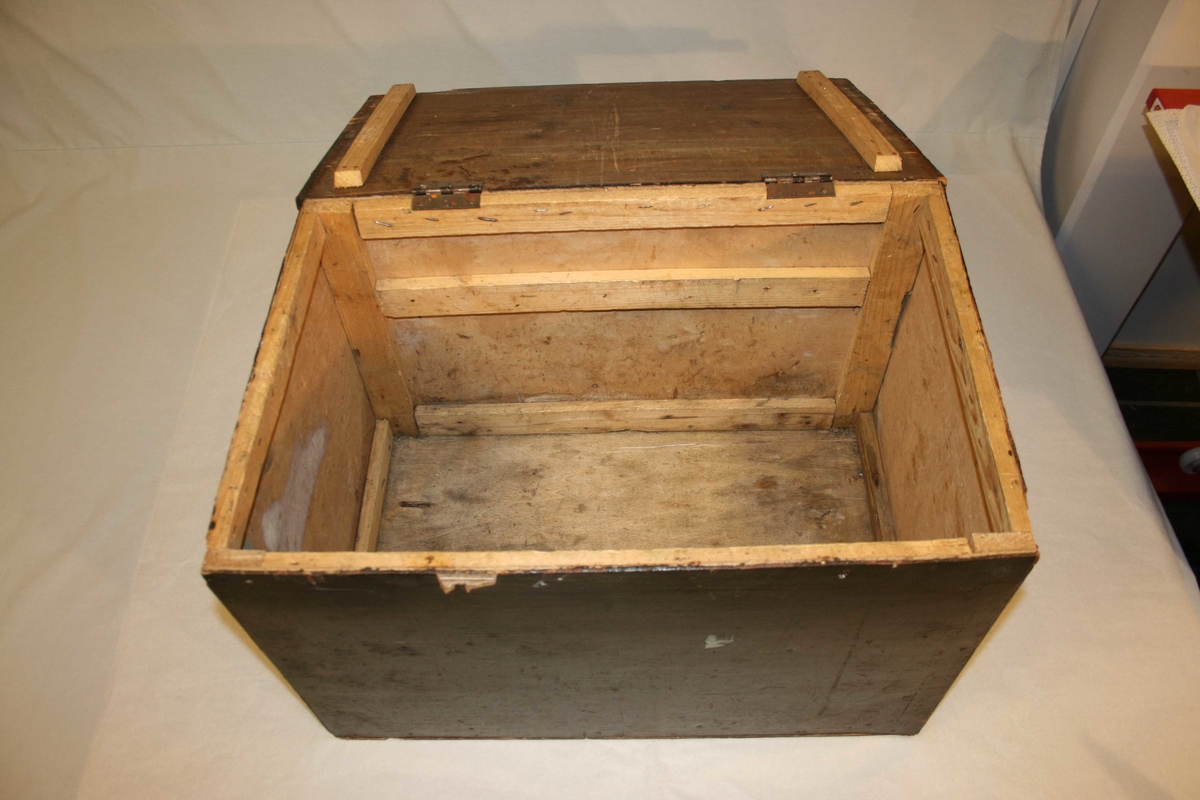 Rektangulær kasse laga av kryssfiner. Ramme og lok av tre. Hengsla lok. Måla svart.
