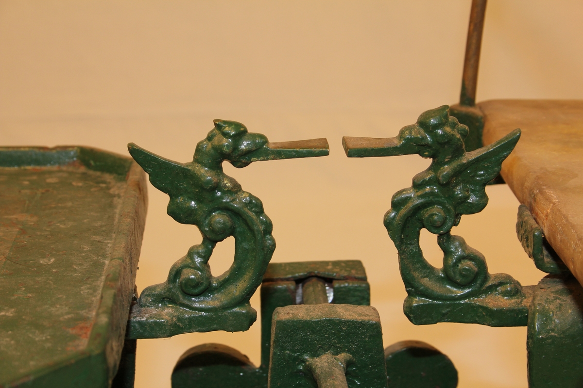 Diskvekt med to skåler. Fire føter med form av dyr-/menneskeskikkelsar. To dyrefigurar med tunger som viser når vekta er i balanse.