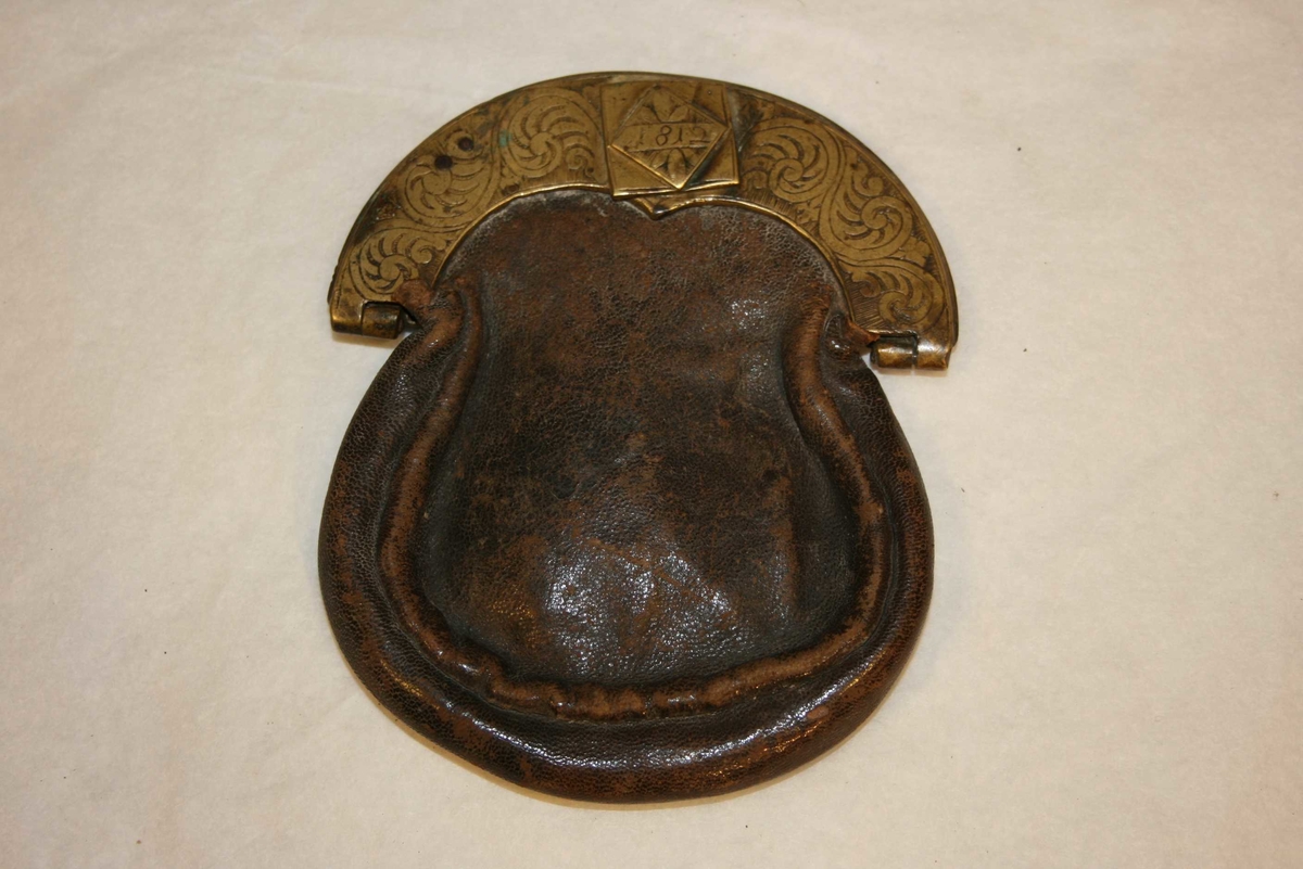 Poseforma skinnpung med messinglås og -beslag. Messing er dekorert med akantusranker.