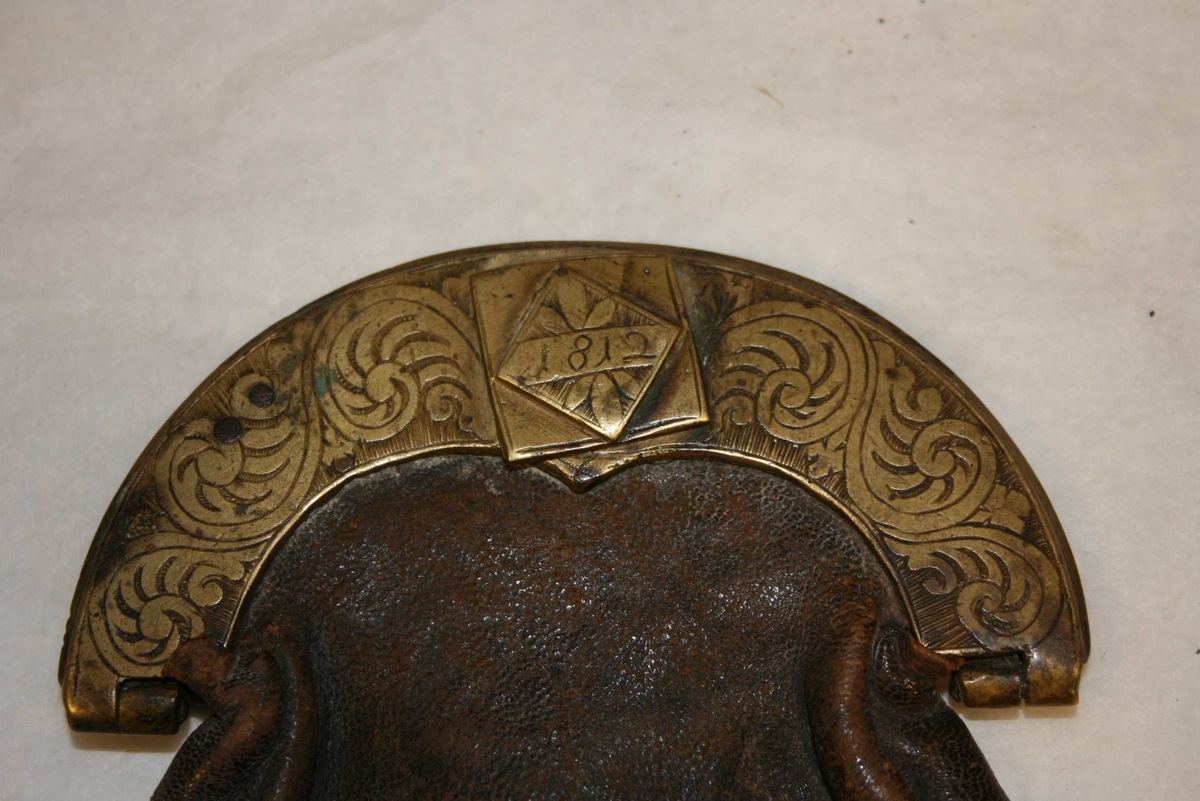 Poseforma skinnpung med messinglås og -beslag. Messing er dekorert med akantusranker.