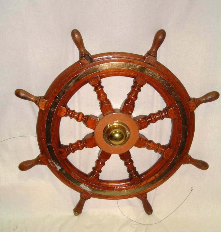 Ratt av cirkelrund träring med utskjutande pinnar runtom som handtag. Ena handtaget är klätt med mässing längst ut. Rattens nav är gjutet och följande text instansat: "Scott & Co Patent Telemotor MacTaggart". Mitt på navet på rattens utsida, en kupa av mässing. Runtom träratten ett infällt mässingsband. 

Modell/Fabrikat/typ: Patent Telemotor MacTaggart
