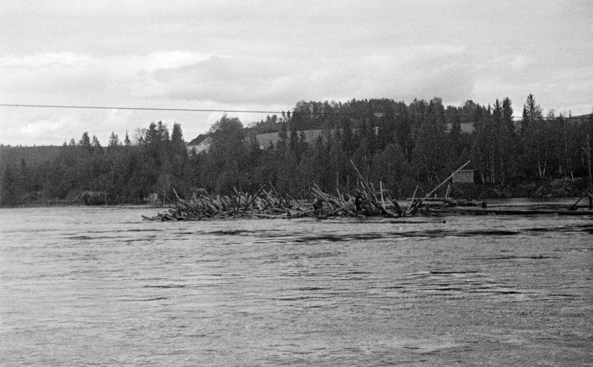 Tømmervase ved Kykkelsrud i Nedre Glomma (Askim i Østfold) i 1943.  Fotografiet viser en del tømmer som hadde stuvet seg sammen, slik at stokkene sprikte i ulike retninger.  Vi skimter fløtere i arbeid på tømmerhaugen.