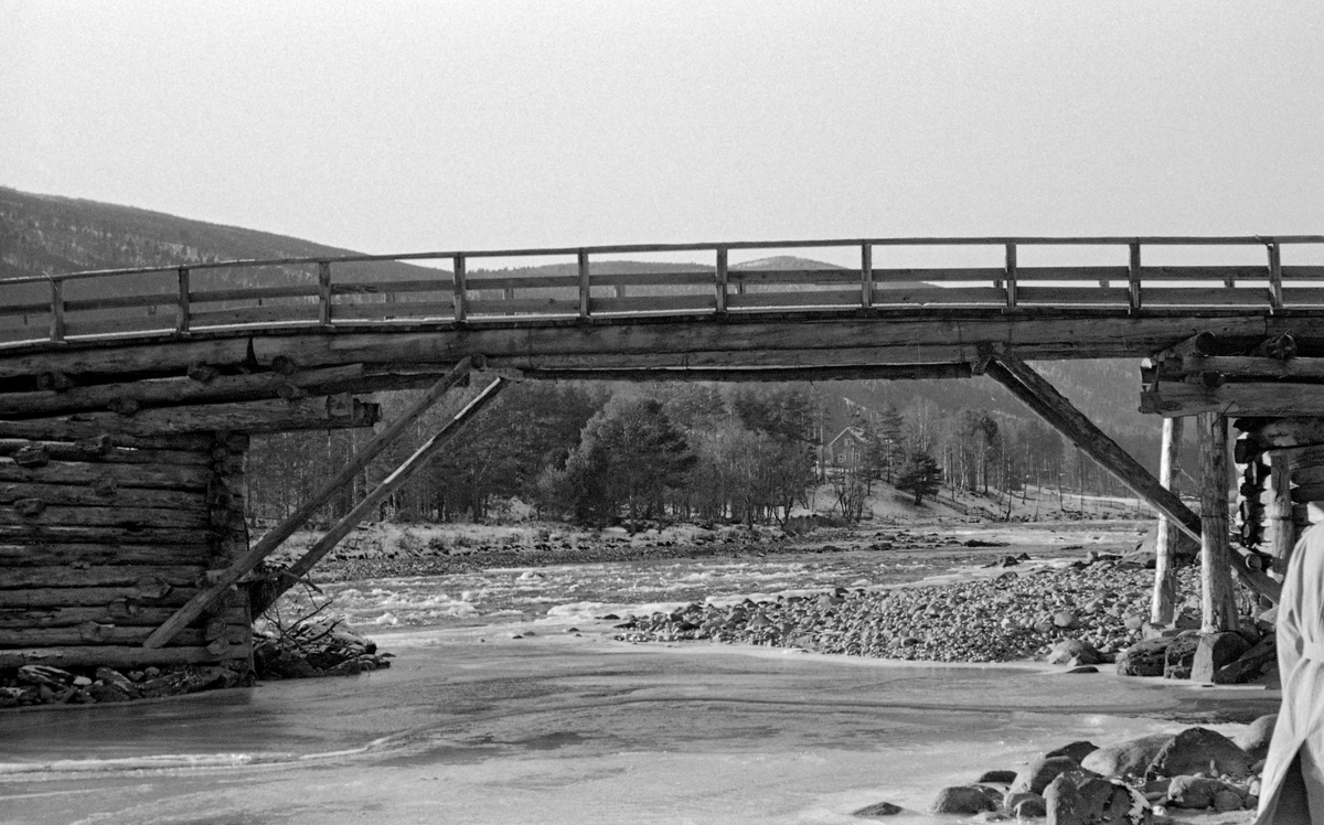 Deler av Ulekleivbrua over Gudbrandsdalslågen på Dovre, fotografert egn kald oktoberdag i 1955.  Dette var ei bjelkebru, bygd av tømmer.  For å kunne nå over det forholdsvis brede elvefaret med dette byggematerialet hadde man reist et brukar – ei steinfylt tømmekiste – på ei røys i elva, mellom landkarene på begge sider.  På denne tømmerkista hadde brubyggerne lagt ei rektangulær ramme med to omfar, som de øverste brubjelkene kvilte på.  Disse var også støttet av skråstivere fra det nevnte tømmerkistefundamentet og fra landkarene på begge sider.  Brua hadde trerekkverk. Trevirket i brukonstruksjonen virket temmelig værslitt da dette fotografiet ble tatt.