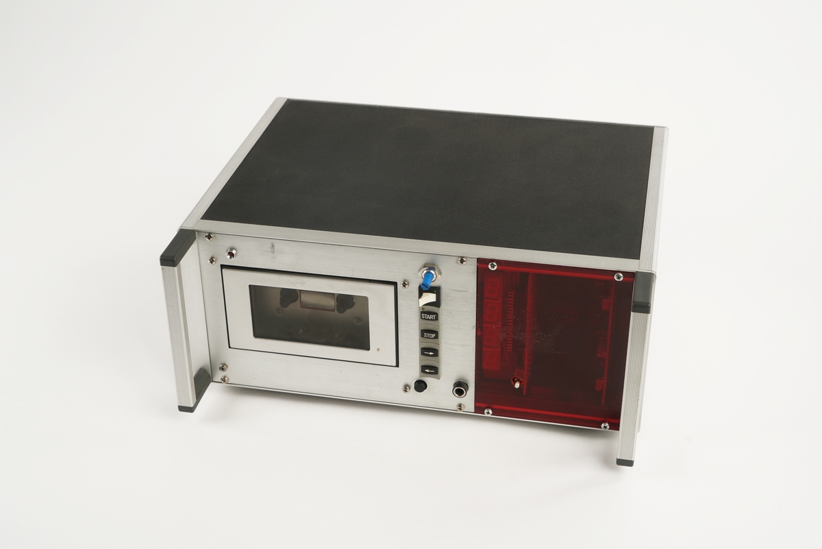 Telefonapparat med taster nummerert fra 0 til 9 og med firkant- og stjernetast. Telefonrør  er tilkoblet med spiralisert ledning. Apparatet er utstyrt med 6 knapper for forhåndsinnstilling av telefonnummer. Videre er det knapper for minne, hold- og høyttalerfunksjon. Volumbryteren er et rullehjul. Fra undersiden kan man dra ut et plastkort/telefonliste. 

I tillegg medfølger to  instrumentbokser med mulighet for å  ta opp og lagre samtaler. I front på den ene er det et vindu med antatt digital tekst og diverse  "softtouch" knapper til å bearbeide opptak. To brytere for antatt å kunne justere lydstyrken. Videre er det montert ulike  utganger for tilkobling av diverse utstyr bl.a. headset. Det er også montert en diskettstasjon med åpning i front. På baksiden av opptakeren er det montert ulike dataporter og strømtilkoblinger. Jordingskabel med skjøtekobling. Strømkabel medfølger.

Den andre boksen er forsynt med to håndtak i front, samt en luke/deksel på venstre side, med gjennomsiktig vindu av plast,  som kan åpnes for isetting av kasettbånd. På høyre side i fronten er det et gjennomsiktig rødt plastvindu hvor det er gjort hull slik at man kommer til en hvit trykkbryter. Fronten er videre påsatt en blå, vridbar bryter, en hvit vippebryter med rød og grønn lampe, samt fire sorte trykkbrytere med hvit tekst: "START" "STOP" og høyre/venstre pil. Nederst er det en sort trykkbryter som formentlig benyttes til å åpne dekslet til kasettbåndet.Til høyre for denne bryteren er det et kontaktpunkt for tilkobling av tilleggsutstyr.
På baksiden av boksen er det fire ulike kontaktpunkter for tilkobling av tilleggsutstyr samt fastmontert strømkabel med kontakt. Videre er det montert en skrubar sikringsholder.
Under boksen er det montert fire, høydejusterbare, ben