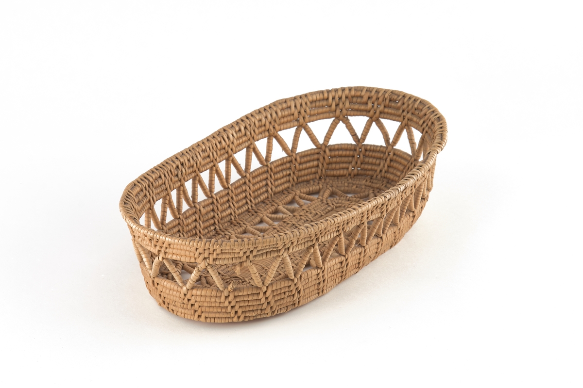 Oval brödkorg av rottågor i björk. Väggarna och bottnen är genombrutna av ett sicksackband.