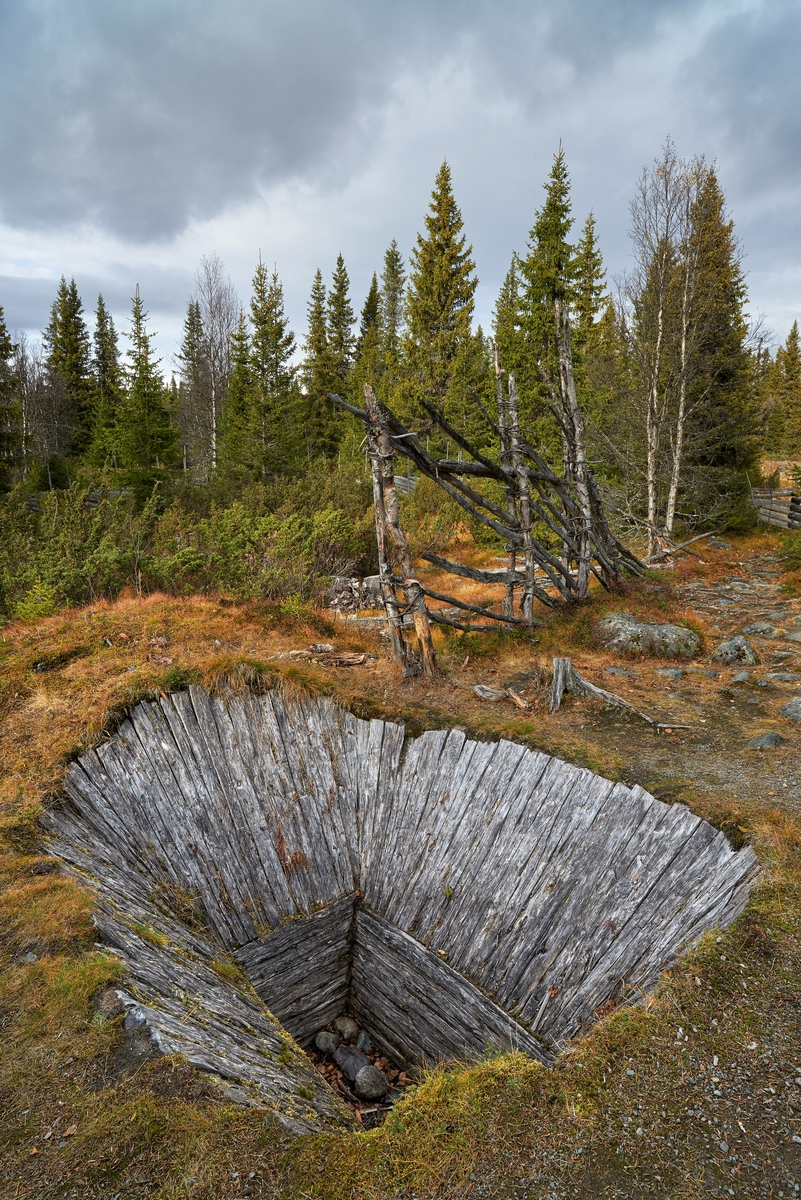 Fangstgrav for elg på Dokkfløy i Vestre Gausdal, rekonstruert på grunnlag av arkeologiske undersøkelser som ble gjort i dette området i forkant av kraftutbyggingsarbeider i slutten av 1980-åra.  Området ligger 700-900 meter over havet.  Her er det fortsatt elgtrekk i mai og i november-desember.  Arkeologene som undersøkte området registrerte 121 groper som man antok hadde vært brukt til fangst, altså som dyregraver.  Disse ligger i rekker, og undersøkelsene viste at det har vært skigardliknende gjerder mellom dem, slik at elg som ville passere ble ledet mot åpningene i disse gjerdene, hvor dyregravene lå.  Ved undersøkelsen av den dyregrava som ble rekonstruert mente arkeologene å kunne påvise spor etter tre konstruksjonsfaser, sannsynligvis fordi dyregrava hadde forfalt og måtte repareres eller gjenoppbygges.  Elggrava består av en oval, traktformet nedgravning (3, 7 X 2, 3 meter i toppen) med en hellingsvinkel på 45 grader ned mot ei rektangulær grop med loddrette vegger i botnen.  Denne nederste delen av grava er så trang at elgen knapt fikk plass til å løfte beina.  Hele fangstgropa er kledd med halvkløvninger av bjørkevirke.  Dette materialet var hardt og glatt, noe som antakelig skulle gjøre det umulig for elgen å kravle seg opp, om den skulle få beina opp fra den nederste, trange delen av gropa.  Det er lagt en jordvoll mot kortsidene av elggrava, altså den retningen elgene kom inn mot grava fra, og den retningen de ville ta for å komme videre.  Disse jordvollene bidro til at fallhøyden ble forholdsvis høy, og at dyret måtte høyt opp for eventuelt å komme ut igjen.  Det ble funnet fragmenter av furuspiler og bjørnemose, antakelig rester av det dekkmaterialet som ble brukt for å skjule gropa for viltet, da den ble arkeologisk undersøkt.  Slikt dekke inngår av ulike årsaker ikke i rekonstruksjonen.  Radiokarbonanalyser av organisk materiale fra de arkeologiske undersøkelsene tyder på at denne dyregravslokaliteten var i bruk fra cirka 200 før Kristus til om lag 500 etter Kristus, og deretter fra omkring 1000 til 1700 år etter Kristus.  Det tok to personer ti dager å bygge denne fangstgrava med de redskapene man mener at de som bygde dem hadde.  Fangstgraver av denne typen ble tildekt med sikte på passiv fangst.  Også dette har vært prøvd på Dokkfløy i samarbeid med fagfolk fra NINA – Norsk institutt for naturforskning.  Arkeologen Harald Jacobsen (1954-2017), som ledet rekonstruksjonsprosjektet, har i ettertid registrert at denne rekonstruksjonen er blitt brukt som modell for elggravrekonstruksjoner flere andre steder, noe han beklager.  Den rekonstruerte fangstgropa på Dokkfløy er nemlig ingen standardmodell som ble brukt alle steder det foregikk passiv fangst av elg til alle tider.  Dette er en spesiell variant som er basert på observasjoner fra arkeologiske undersøkelser nettopp på Dokkfløy.