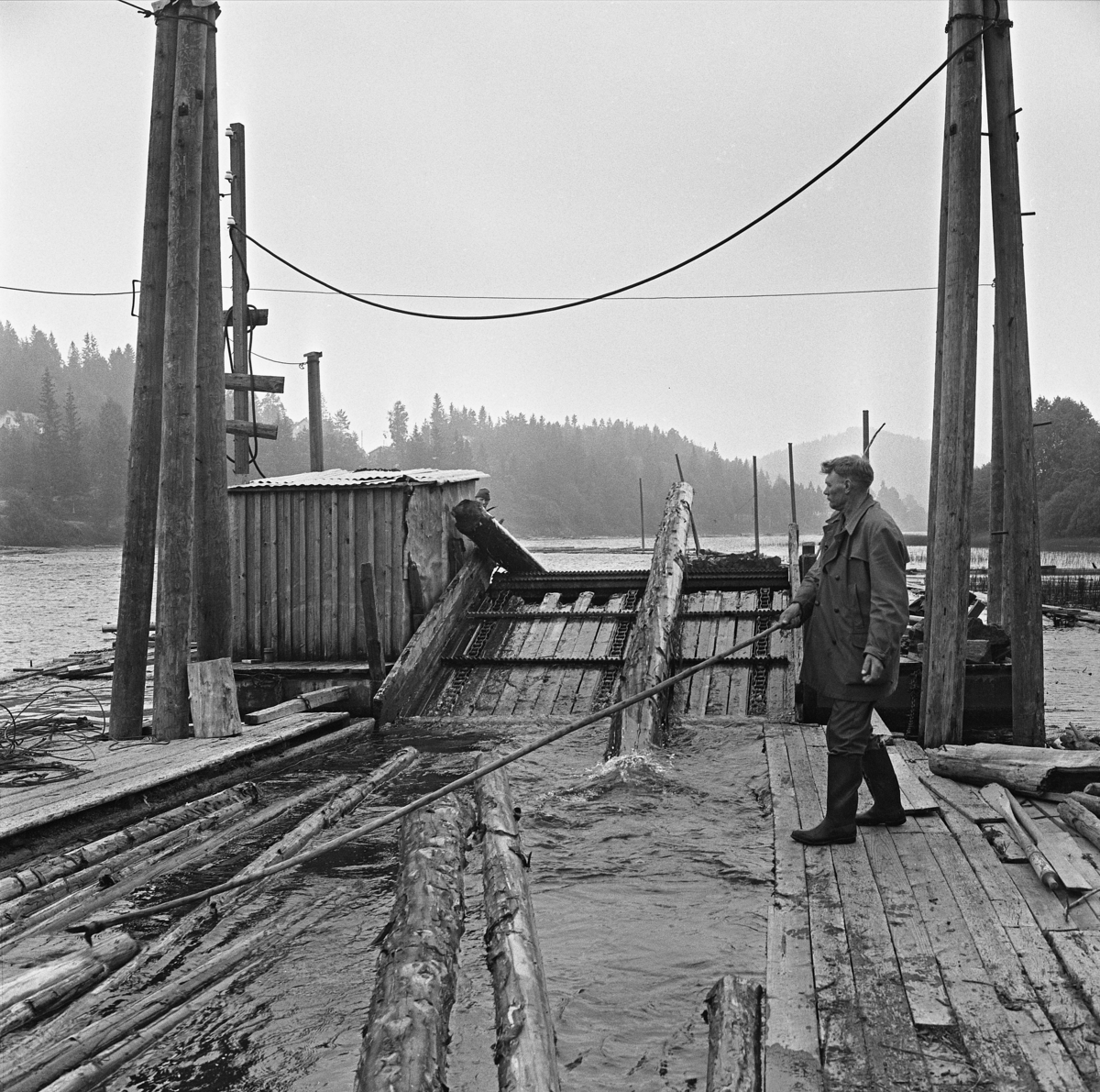 Fra lense- og sorteringsanlegget for tømmer i en stilleflytende del av Nidelva ved Messel i Froland, altså i den nedre delen av Arendalsvassdraget.  Fotografiet viser hvordan sortert tømmer ble ledet gjennom en kanal mellom to flytende gangbruer mot en kjerrat, som løftet stokkene opp og kastet dem ned i et bakenforliggende kammer der de ble liggende oppå hverandre.  Når dette kammeret var fullt inneholdt det cirka 20 kubikkmeter virke.  Dette bandt man sammen med en vaier med kjettingbindsel i endene.  Dermed var virket klart for sleping videre til industrielle kjøpere her ved den nedre delen av vassdraget.  På gangbrua til høyre i dette bildet står en fløter med en lang hake, som han bruker til å trekke stokker som kommer drivende inn mot kjerraten.  Den er formet som et skråplan med endeløse belter som trekker tverrstilte stålstenger med takkete «kammer» på toppen rundt og rundt.  Det er disse som trekker stokkene opp, for så å kaste dem ned i det bakenforliggende kammeret.  Til venstre for kjerraten ser vi et lite skur med pulttak, antakelig for motoren som drev kjerraten.  En telegrafstolpe ved siden av tyder på at denne hadde elektrisk drift.  Ellers viser fotografiet hvordan hele kjerratanlegget var forankret i kraftige pæler som var drevet ned i elvebotnen tett ved siden av hverandre ved hjelp av en rambukk og skrudd sammen i toppen.  Hovedforankringene her var pæleansamlinger som er lagd av tre-fire stokker. 

Det året da dette fotografiet ble tatt, i 1970, hadde imidlertid styret i Fellesfløtningsforeningen vedtatt at all fløting mellom Messel og Asdal, med rodene Rore og Søndle, skulle trekkes ut av foreningens virkeområde. I praksis betydde dette at all tømmersortering skulle skje ved Messel. Derfra skulle virket transporteres videre på lastebiler, enten til Arendal eller direkte til tømmerkjøpernes produksjonsanlegg. Året etter, i 1971 ble det bare fløtet et lite parti fra Åmot til Messel. Med det var tømmerfløtingas tid i Arendalsvassdraget over.

Kort historikk om fløtinga i Arendalsvassdraget finnes under fanen «Andre opplysninger».