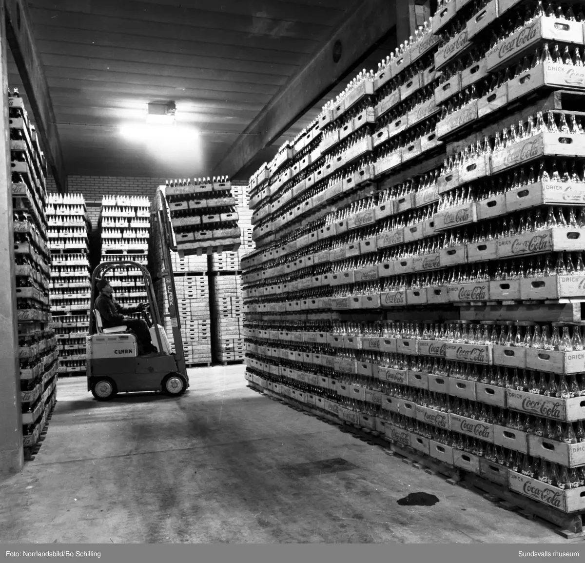 Coca-Cola-fabriken vid Bultgatan i Nacksta. Exteriörbilder samt bilder från lagret, en man kör truck bland tomma och fyllda flaskor.