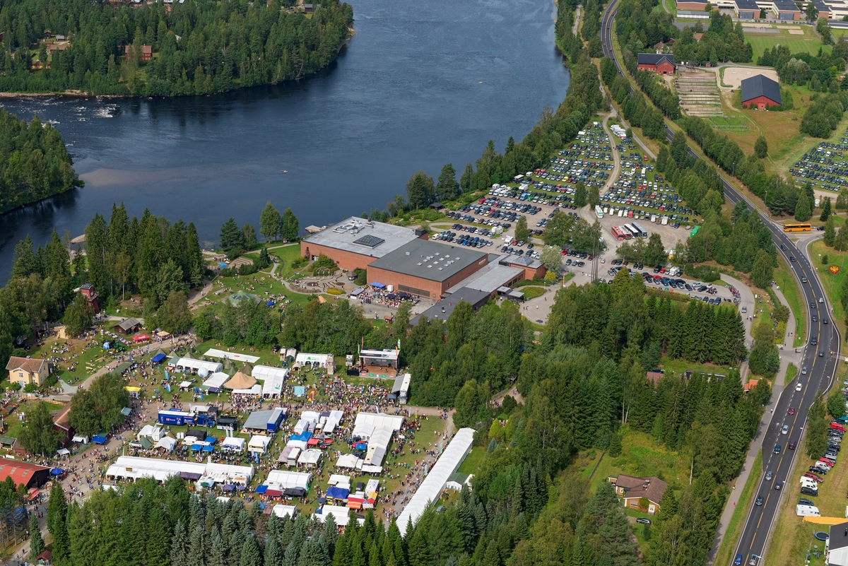 Norsk Skogmuseum i Elverum, sett fra lufta, 9. august 2014.  Fotografiet er tatt fra sør.  Dette var lørdagen under De nordiske jakt- og fiskedager dette året, noe som preget aktiviteten på museet og i området omkring.  Museumsbygningene, to blokker på 40 X 40 meter, utført i betong med teglsteinsforblending, ligger sentralt i bildet.  På parkeringsplassen øst og nord for disse bygningene, og på Nordjordet mellom riksveg 2 (Solørvegen) og Glomma var det parkert biler, like ens på Prestegardens jorde mot krysset mellom riksveg 2 og Storgata.  På klokkergarden Fossum og det som en gang var åkerarealer på denne eiendommen (nederst til venstre i bildeflata) var det telt som var utsalgssteder for mange av arrangementets utstillere, omkranset av mange mennesker.  

Den dagen dette fotografiet ble tatt var det 13 148 gjester som løste billetter til De nordiske jakt- og fiskedager.  I løpet av de fire dagene arrangementet pågikk var det 31 919 mennesker som besøkte museet. 