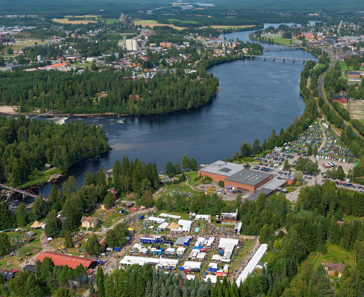 Norsk Skogmuseum i Elverum, sett fra lufta, 9. august 2014.  Fotografiet er tatt fra sør.  Dette var lørdagen under De nordiske jakt- og fiskedager dette året, noe som preget aktiviteten på museet og i området omkring.  Museumsbygningene, to blokker på 40 X 40 meter, utført i betong med teglsteinsforblending, ligger sentralt i bildet.  På parkeringsplassen øst og nord for bygningene, og på Nordjordet mellom riksveg 2 (Solørvegen) og Glomma var det parkert biler.  På klokkergarden Fossum og det som en gang var åkerarealer på denne eiendommen (nederst i bildeflata) var det telt som var utsalgssteder for mange av arrangementets utstillere, omkranset av mange mennesker.  Til venstre i bildet ser vi deler av Prestøya, med Norsk Skogmuseums friluftsmuseum, der det var stor hundeutstilling denne dagen.  På motsatt side av Glomma og Prestfossen ser vi Glomdalsmuseets friluftsmuseum med bydelen Vestad ovenfor.  

Den dagen dette fotografiet ble tatt var det 13 148 gjester som løste billetter til De nordiske jakt- og fiskedager.  I løpet av de fire dagene arrangementet pågikk var det 31 919 mennesker som besøkte museet. 