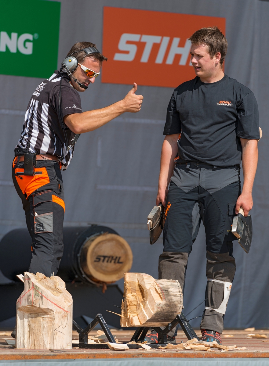 Fra nordisk mesterskap i «Stihl timbersports» under De nordiske jakt- og fiskedager på Norsk Skogmuseum i Elverum torsdag 7. august 2014.  Her arrangerte skogsredskapsprodusenten Stihl konkurranser, der deltakernes hurtighet og presisjon i arbeid med øks, stokksag og motorsag ble bedømt og premiert.  2014 var det første året denne konkurransen var lagt til Norsk Skogmuseum og De nordiske jakt- og fiskedager.  Da dette fotografiet ble tatt hadde en av deltakerne (til høyre) nettopp delt en kabbe i to ved hjelp av øks, en øvelse der tidsfaktoren var viktig i forhold til konkurrenter som kappet andre kabber med samme dimensjon med samme redskap.  Til venstre i bildet ser vi en dommer som vender tommelen opp, antakelig som et signal om at den nettopp gjennomførte øvelsen er godkjent.  En jury fra arrangørenes stab kåret for øvrig aktivitetene på Stihls scene til «Årets event» med følgende begrunnelse: «Formidler kunnskap om tradisjonelle teknikker i en moderne og underholdende form.  Stor publikumsappell med spektakulært show. » 

«Stihl timbersports» er en internasjonal konkurranse for tømmerhoggere. Den har sitt utspring i Canada, USA og New Zeeland, der skogsarbeidere alt på 1800-tallet skal ha arrangert lokale konkurranser for å kåre den beste blant dem. Med tida ble det utviklet tester for vurdering av styrke og ferdighet i konkurranser på høyt nivå med profesjonelle aktører. I 1985 stiftet STIHL Inc. USA, i samarbeid med sportskanalen ESPN, det som ble «Stihl timbersports series», som er en konkurranseserie i USA og Europa.  2014 var det første året slike konkurranser ble avviklet i Norge. Konkurransene består av seks grener: tre med øks, to med motorsag og en med svans. Øvelsene simulerer felling av stående trær og kapping av felte trestammer. Utøverne får testet arbeidsteknikk, styrke og utholdenhet.