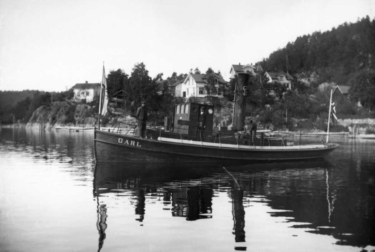 Skienvassdragets Fellesfløtningsforenings slepebåt «D/S Carl», fotografert ved Løveid, ytterst i Norsjø, antakelig da båten var nyinnkjøpt i 1911.  Dette fartøyet kjøpte fløtingsforeningen fra Gøteborg, der det hadde gått under navnet «D/S John».  Skiensvassdragets Fellesfløtningsforenings styre eller direksjon skal ha valgt Carl-navnet for å hedre brukseier Hans Carl Hansen (1844-1925), som var medlem av organisasjonens styre i perioden 1897-1917.  D/S Carl ble bygd ved Eriksbergs mekaniska Verkstad I Gøteborg i 1894, men var noe ombygd i 1902 og hadde fått ny dampkjel i 1904, slik at det var et forholdsvis moderne og velfungerende fartøy Skiensvassdragets Fellesfløtningsforening kjøpte for om lag 12 000 kroner i 1911.  D/S Carl gikk som slepebåt i Skiensvassdraget fram til 1936.  Her er fartøyet fotografert fra babord side med en mann på fordekket, en i styrhuset og en på akterdekket.  Båten hadde en vimpel i baugen, antakelig med navnet «Carl», og et norsk flagg i akterenden.  Skorsteinen var merket med initialene til Skiensvassdragets Fellesfløtningsforening. 