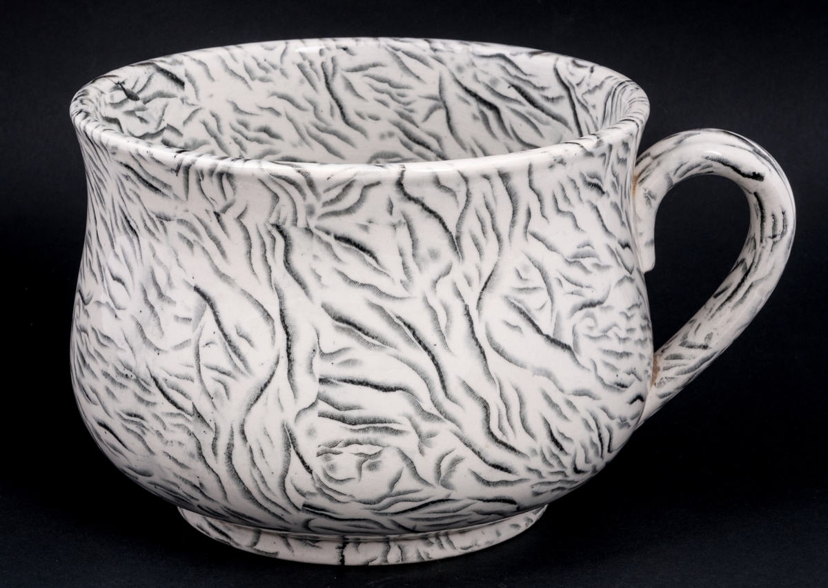 Tvättservis av vitt porslin med marmorering i grått. Servisen består av handfat, potta, en avlång tvålkopp och en kvadratisk, båda med lock. Handfatet stämplat Gustafsberg.