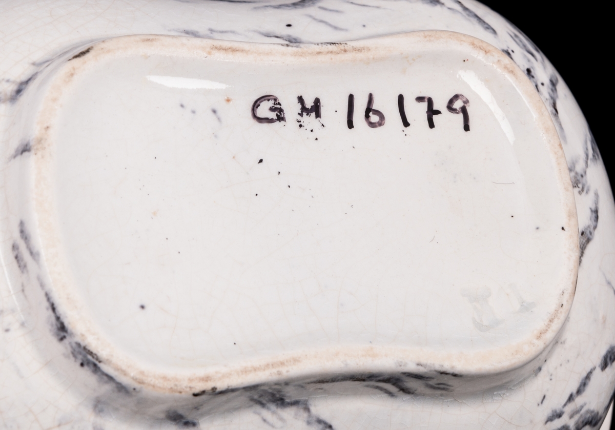 Tvättservis av vitt porslin med marmorering i grått. Servisen består av handfat, potta, en avlång tvålkopp och en kvadratisk, båda med lock. Handfatet stämplat Gustafsberg.