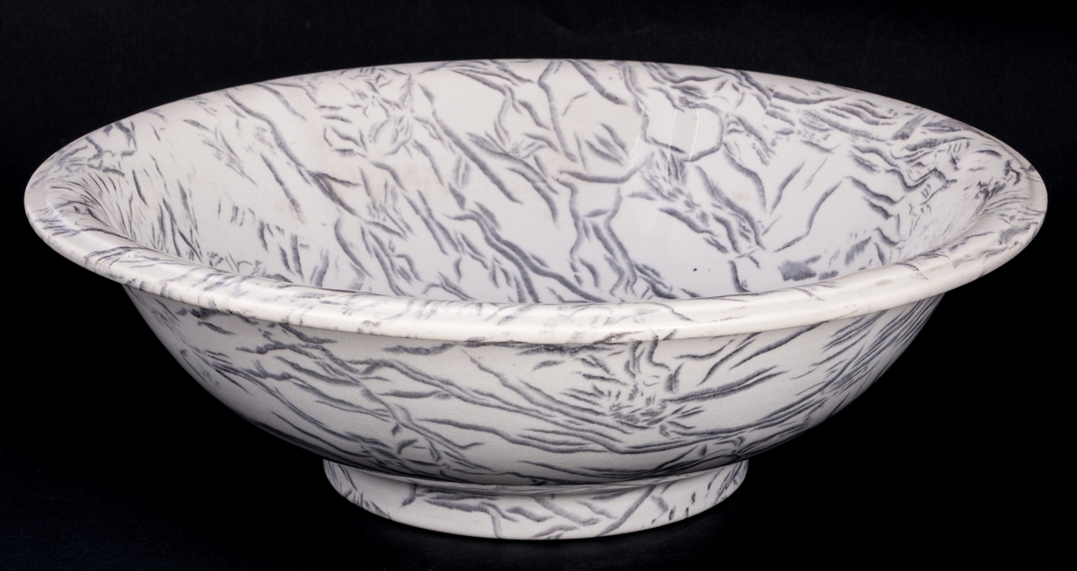 Tvättservis av vitt porslin med marmorering i grått. Servisen består av handfat, potta, en avlång tvålkopp och en kvadratisk, båda med lock. Handfatet stämplat Gustafsberg.