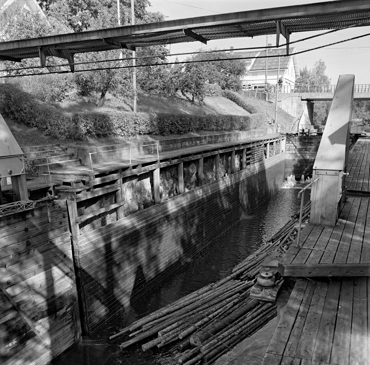 Strømsfoss sluse i Aremark i Østfold.  Fotografiet er tatt i 1982, som var den siste sesongen det ble fløtet tømmer i Haldenvassdraget.  Strømsfoss sluse hadde bare ett slusekammer, og det hadde en løftehøyde på cirka to meter mellom kanalen fra Aremarksjøen på nedsida og Strømselva på oversida.  Dette fotografiet er tatt mot slusekammeret på et tidspunkt da det var nedtappet og nedre sluseport sto åpen. Ei slusevending – ei lenke med fire bunter ubarket massevirke i tre meters lengder – lå fortsatt i kammeret, men skulle snart «spyles ut» ved at det ble tappet vann fra bunnlukene i de øvre sluseportene.  I bakgrunnen ser vi vegbrua som førte fylkesveg 124 over sluseanlegget og bygningen som huset landhandleriet på Strømsfoss.

En liten historikk om tømmerfløting og kanaliseringsarbeid i Haldenvassdraget finnes under fanen «Opplysninger».