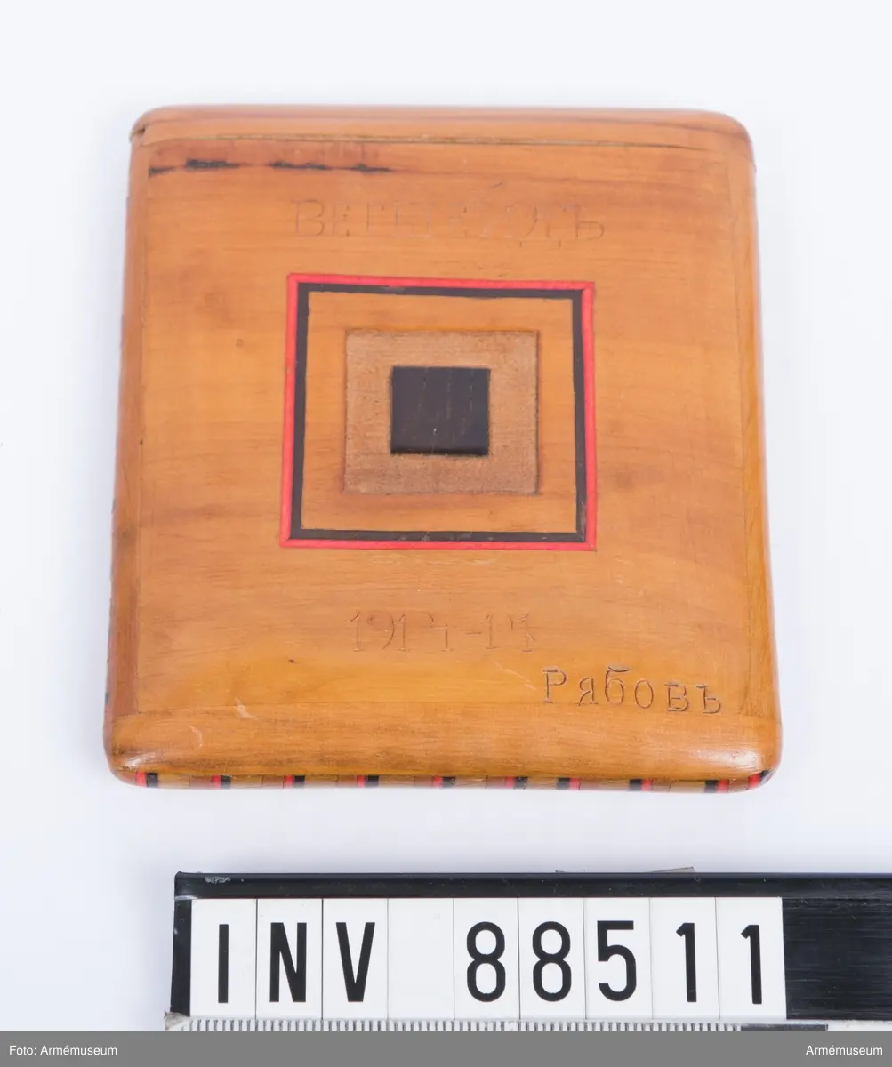 Etuiet är tillverkat i trä med inslag av intarsia. Det är lackat och dekorererat med fyrkanter i rött och svart på båda sidorna, samt försett med  streck i rött och svart längs med alla fyra sidokanter. Inuti ligger en handskriven lapp.