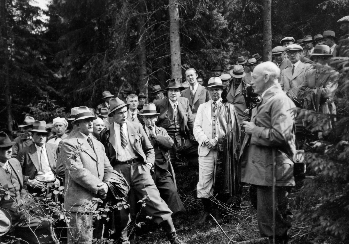 Professor Agnar Johannes Barth (1871-1948) taler under Norsk Forstmannsforenings studieutferd i Kongsvinger-traktene i Hedmark sommeren 1938.  Barth står til høyre i bildet med ei forsamling av lyttende yngre kolleger foran seg.  Fotografiet er tatt på en hogståpning i et grandominert bestand.  Lokalavisa «Indlandsposten» refererte professorens syn på «gjenreisningen av våre vanskjøttede og forhuggne skoger» slik:

«Skogvidenskapens dyrkere har lagt frem klare beviser for nødvendigheten av skogbehandling på naturlig grunnlag.  Jeg ser et økonomisk og samfundsmessig skogbruks opgave i den størst og best mulige produksjon, og jeg mener at man opnår dette ved å økonomisere med de nuværende skogers og bestands produktive og kvalitativt gode elementer.  Jeg mener at denne opgave må gå foran nyskapningen av skog, dog uten at nyskapningen skal forsømmes.  Jeg går ikke av veien for en radikal og hurtig foryngelse av helt uveksterlige, syke og stekt oprevne, for glisne skogbestand eller for en bortrydning av produksjonsudyktig underskog og forhåndsgjenvekst på foryngelsesflatene.  Men det bør prinsippmessig tas vare på alle ennu produksjonsdyktige treindivider, så lenge deres vekstydelse har større verdi enn den ungskogen som de beskytter uten fare for ungskogens videre utvikling.  I den utstrekning som på ethvert sted er nødvendig for å skape nye og tette veksterlige skogbestand, når de gamle har utspilt sin rolle, bør man også benytte sig av alle rasjonelle hjelpemidler i jordbunnhevdens og skogforyngelsens tjeneste; jeg kan nevne markberedning, lyngbrennig, såing, plantning og grøfting.  Endelig bør det legges vekt på å gjeninnføre løvtrærne i våre barskoger for igjen å sanere den på grunn av løvskogens utryddelse over store arealer ved råhumusdannelse degenererte skoggrunn.»

Barth var den sentrale talsmannen for «bledningsbruk» i Norge.  Bledningsbruket var en avvirkningsmetodikk som var orientert mot enkelttrær, ikke mot bestandsgrupper.  Her var det altså ikke snakk om sluttavvirkning og klare generasjonsskifter i skogbestandene, men om suksessiv utplukking av enkelttrær etter vurderinger av hogstmodenhet og av fristillingseffekter på omkringstående ungskog.  Barth og hans meningsfeller så på dette som en «naturlig, biologisk begrunnet skogskjøtsel».  Da dette fotografiet ble tatt orienterte mange av Barths yngre kolleger seg mer mot «bestandsskogbruk», med snauhogster og påfølgende planting, som skulle gi ensaldrete bestand av bare ett treslag.  Dette prinsippet hadde lenge vært praktisert i andre land, til en viss grad også i Sverige.  Også i Norge var stadig flere fagfolk som mente at bestandsskogbruk med snauhogster og ensaldrete bestand var bledningsbruket overlegent, både med hensyn til produktivitet og virkeskvalitet.  Denne diskusjonen opptok åpenbart også deltakerne under Forstmannsforeningens utferd i 1938, som også tiltrakk seg en del svenske fagfolk.