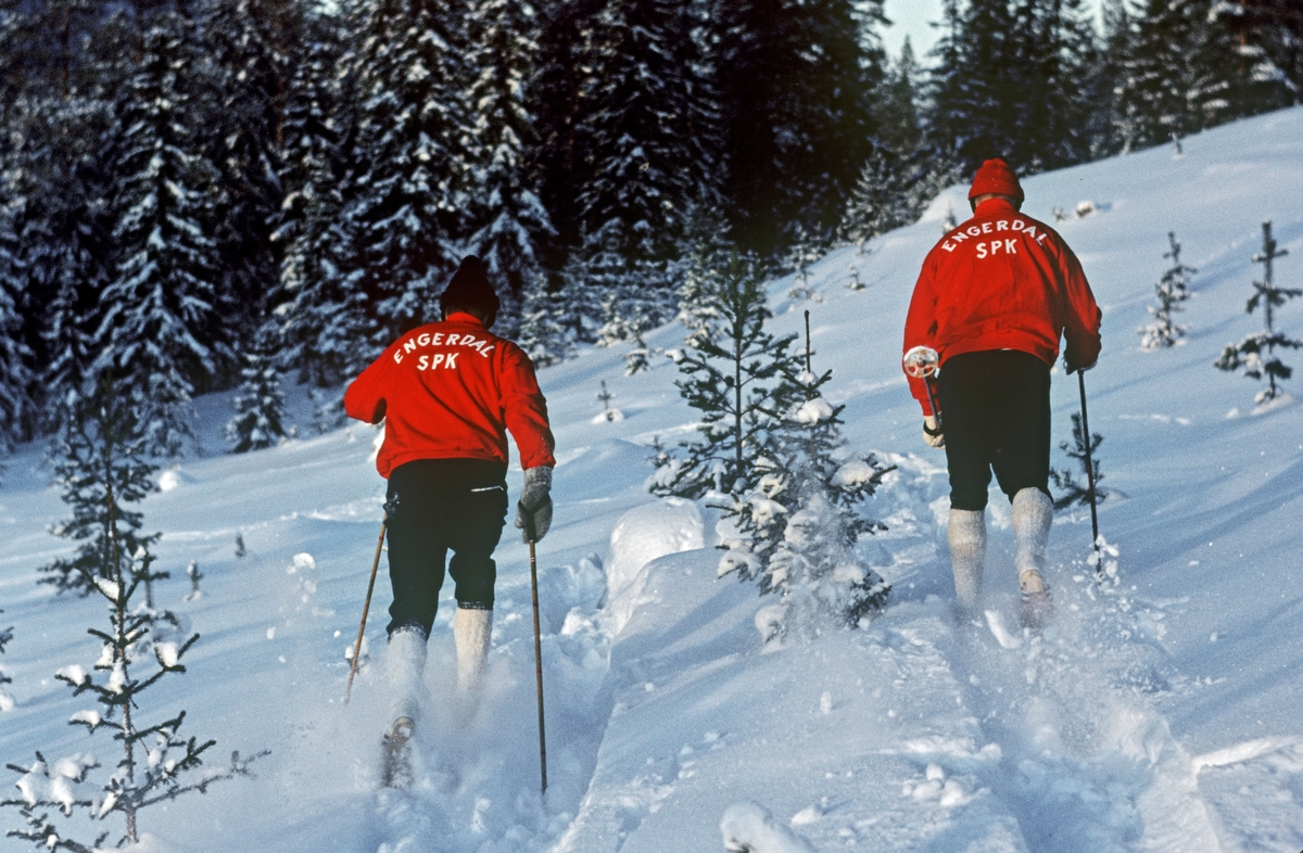 Arrangert treningsbilde av tvillingbrødrene Jo og Gjermund Eggen, tatt i 1966, som var det beste året i begge brødrenes karrierer.  Fotografiet er tatt på ei åpen, snødekt flate i skogen, der brødrene gikk parallelt, med fotografen bak seg.  Begge var iført svarte nikkersbukser med kvite strømper og hadde røde treningsjakker med «ENGERDAL SPK» med kvite bokstaver på ryggsida.  Eggen-brødrene gjorde seg nasjonalt bemerket under norgesmesterskapet på ski i 1964.  Også 1965-sesongen ble god.  I 1966 ble begge tatt ut i langrennstroppen til verdensmesterskapet på ski, som ble avviklet i Holmenkollen.  Begge fikk gå åpningsdistansen 30-kilometer, som de regnet for sin beste øvelse.    Resultatet ble skuffende – Gjermund ble nummer 16 og Jo nummer 27.  For Jos del betydde dette at mesterskapet var over.  Gjermund fikk derimot starte også i det øvrige langsrennsprogrammet, og resultatet oversteg både hans egne og andres forventninger: Gjermund Eggen ble verdensmester på 15- og 50 kilometer, og ankermann på det seirende norske stafettlaget.   For dette ble han hedret med Sportsjournalistenes statuett, Morgenbladets gullmedalje og Olavsstatuetten.  Seinere fikk han også Holmenkollmedaljen.  I 1966 ble Gjermund og Jo også nummer 1 og 2 på 30-kilometeren i norgesmesterskapet, og sammen med John Harviken vant de NM-stafetten for Engerdal Sportsklubb.  Gjermund var med på langrennslandslaget også i åra som fulgte.  Han vant 30-kilometeren under Svenska skidspelen i 1968 og 15-kilometeren under Lahti-spelen i 1969.  I OL i Grenoble ble han nummer 34 på 30-kilometeren.  Brødrene hevdet seg ellers godt i regionale renn gjennom mange år.  Jo og Gjermund delte gjerne den sportslige suksessen med bygdesamfunnet de hadde vokst opp i.  I perioden 1968-1983 ble det produsert ski i Engerdal under navnet «Eggen».

Ut fra dette fotografiet kan det synes som om brødrene trente side om side.  Slik var det egentlig ikke.  I forbindelse med Gjermund Eggens suksess under ski-VM i Oslo i 1966 uttalte Jo Eggen følgende om forholdene mellom tvillingbrødrene som skiløpere:

«…. I sporet slår han meg bestandig.  Det er bare under trening jeg greier å måle meg med ham.  Aldri har han da gått fra meg, men så har vi da heller ikke trent så mye sammen.
- Ikke det?
- Nei, det har lett for å bli konkurranse ut av det.  Vi fant ut at vi ville «drepe» hverandre skulle vi daglig trent sammen.  Derfor har vi valgt å gå forskjellige turer.  Gjermund har forresten flere langturer bak seg enn meg.  Og her tror jeg mye av hemmeligheten bak hans fenomenale styrke ligger.» (Fra Hamar Arbeiderblad, 28. februar 1966)
