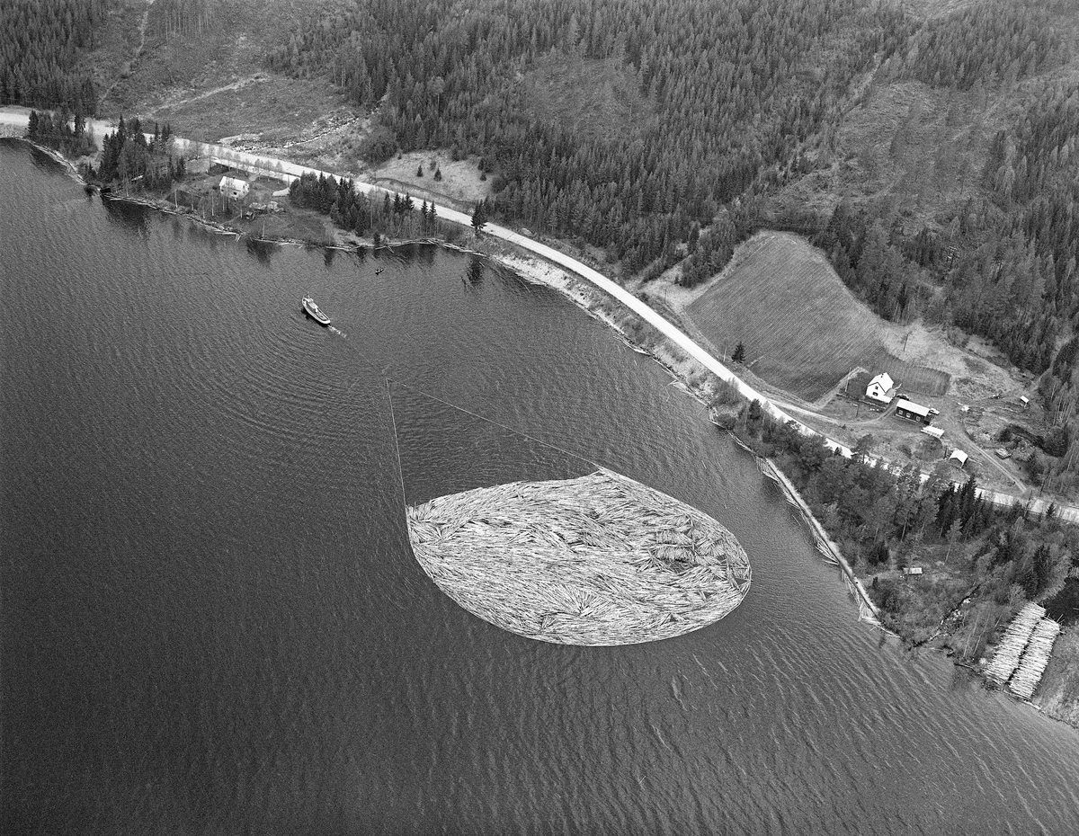 Flyfotografi, tatt over Fiskvikstøa i Ytre Rendalen, på Storsjøens vestside i 1981.  Vi ser hvordan riksveg 30 (her også kalt «Gamle kongeveg») slynget seg langs strandlinja. På vannspeilet ser vi en tømmerbom som ble slept sørover av tømmerslepebåten «Storsjø».  Det tok vanligvis drøyt 30 timer å trekke en slik ringbom fra området ved Åsheim i nordenden av innsjøen til utløpet i elva Søndre Rena, om lag 36 kilometer lengre sør.  Med de store tømmermengdene som ble fløtet i 1950- og 60-åra ble det gjerne omkring 30 turer, og sesongen varte om lag to måneder.  Da dette fotografiet ble tatt, i 1981, kunne 10-12 ringbommer romme de cirka 17 000 kubikkmeterne med slipvirke som skulle fløtes ut av Rendalen.  Virksomheten ble avviklet etter 1984-sesongen.  Ved høyre bildekant skimter vi deler av ei tømmervelte for maskinelt utislag av tømmer som ble fraktet til hovedvassdraget med lastebil, noe som ble stadig vanligere de siste par tiåra det var fløting i Glommavassdraget.