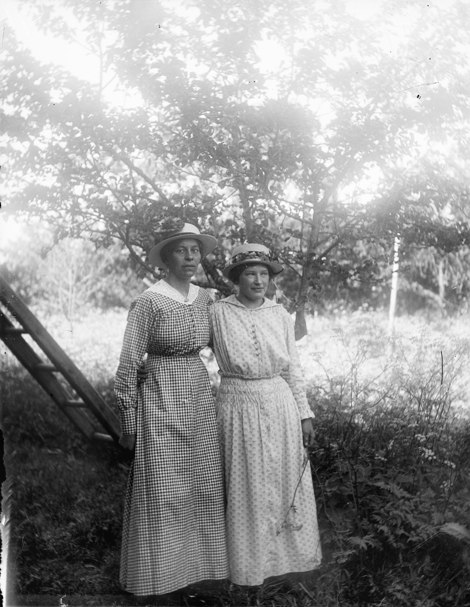 Hildegard Pettersson och ytterligare en person i trädgården i Sävasta, Altuna socken, Uppland