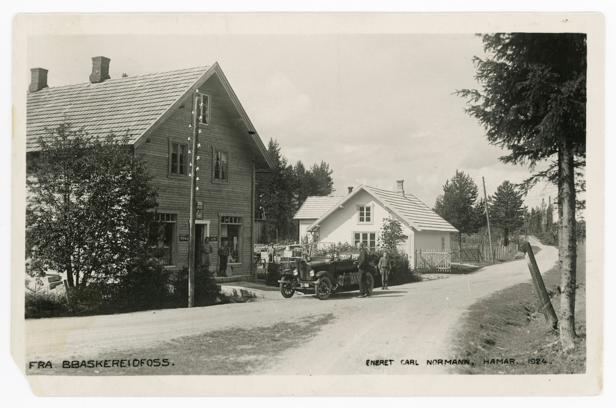Landhandleri ved Solørvegen, like ved avkjøringa til tettstedet Braskereidfoss fra nord.  Fotografiet er tatt fra vegkrysset.  Landhandleriet lå i en toetasjes, bordkledd bygning med inngang og «utstililngsvinduer» på den gavlveggen som vendte mot vegen og ferdelsåra.  Et par ungdommer sto på trappe til butikken da bildet ble tatt.  et par andre viste interesse for bilen som sto parkert ved vegkanten framfor butikken.  I bakgrunnen ser vi ei kvitmalt, lita stue.  Opptaket skal være gjort i 1924.