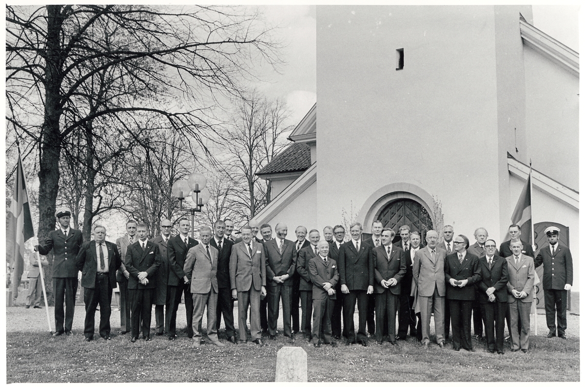 TGOJ-dagen 1973. Anställda vid Trafikaktiebolaget Grängesberg–Oxelösunds Järnvägar fotograferas framför Julita kyrka. Fanbärare Ulf Nilsson till vänster, och Leif Rehnberg till höger. Dåvarande TGOJ-chefen Åke Karlström syns i mitten i bakre raden.