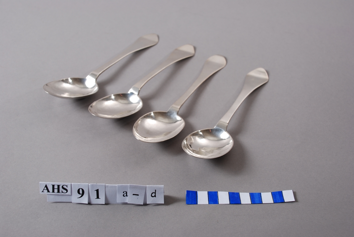 Spiseskje i sølv med produksjonsstempel og inngraverte initialer. Skjebladets bakside inngravert med dekorering av rokokkobladverk.