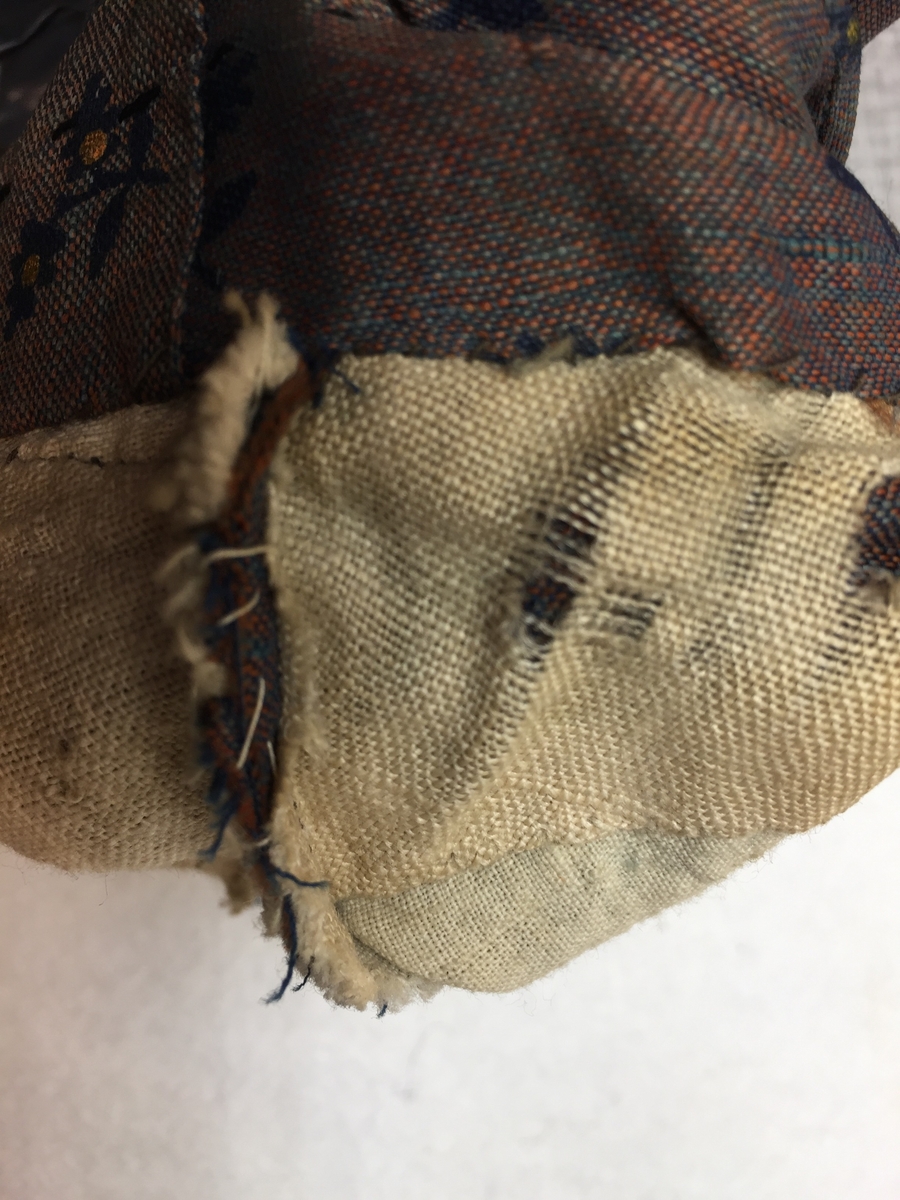 Kjole sammensydd av liv og skjørt med belte i livet med sløyfe i samme stoff. Halvull verkenstoff med trykte blomster. Sydd i Sørum i Akershus ca 1860 og senere brukt på Hamar. Skjørtet har mye håndsøm men vi ser også maskinsøm. Skjørtet er fóret med en skoning av lin i nedre kant. Det er også festet et grønt smalt bånd som slitekant. Overdelen er fóret med ufarget linstoff. Svart fløyelsbånd er festet 1,5 cm fra ermekanten.