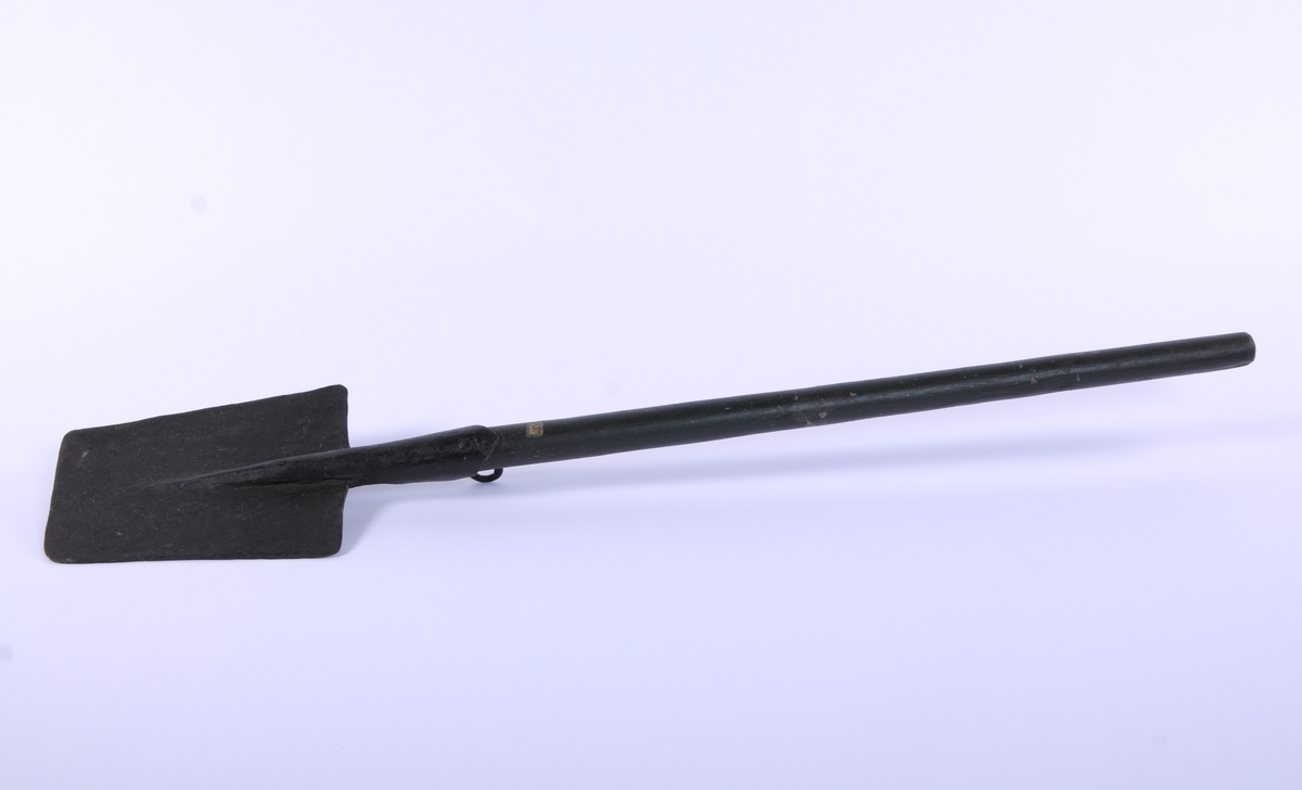Langt, rett skaft stukket gjennom falen, ender i et spor på spadens iunderside. rett, trapesformet blad. Kraftig krok på skaftets underside, ved falen.
3 uidentifiserte stempler på bladets overside
