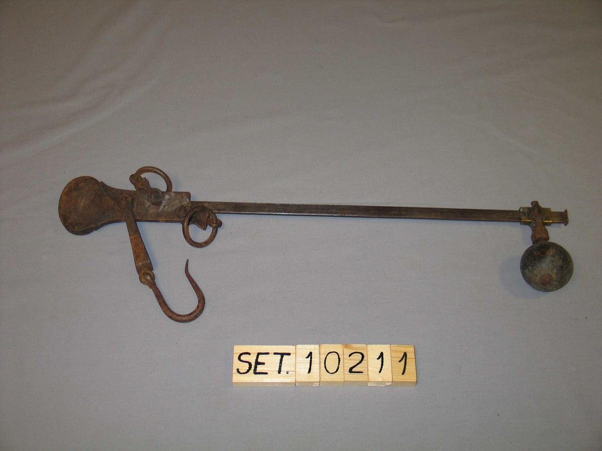 Vektarm av jern med lodd, krok og oppheng. 