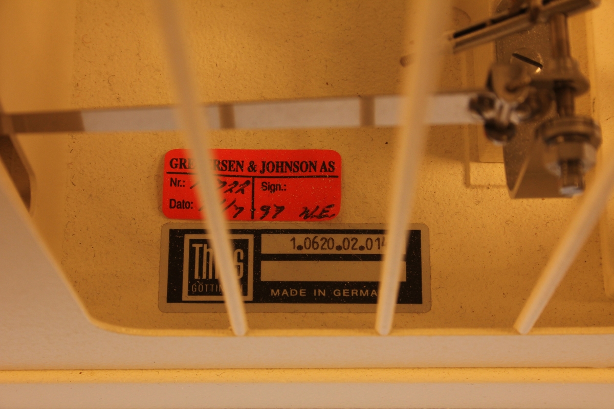 Kvit metallboks med følarar for temperatur og luftfuktigheit. Rulle som dreier og set av måleresultat kontinuerleg. Fjørbelasta skrue som må trekkast opp ein gong i veka for at rulla skal svive.