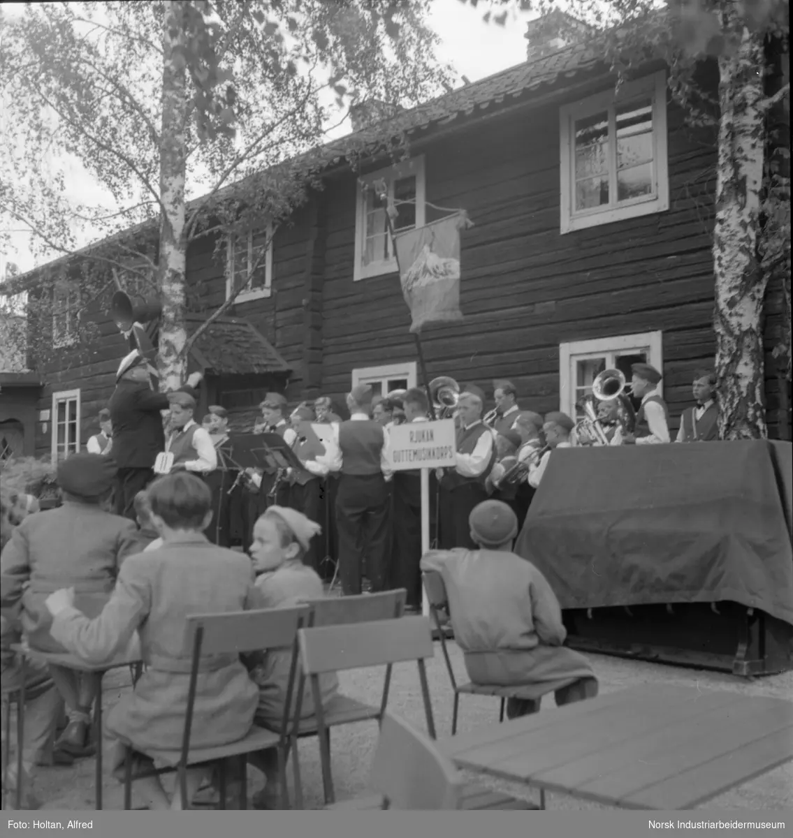 Rjukan guttemusikkorps spiller utenfor laftet bygg.