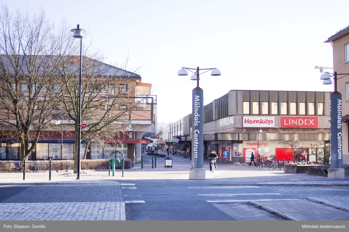 Vy från Storgatan mot Brogatan, år 2015. Till höger skymtas höghuset på Storgatan 32A. Platsen där den vänstra "Mölndals Centrum"-skylten står, blev senare Ulla Jacobssons Plats. Bild 4: till vänster ses Bergmansgatan. Dokumentation av platsen innan rivning och nybyggnation.