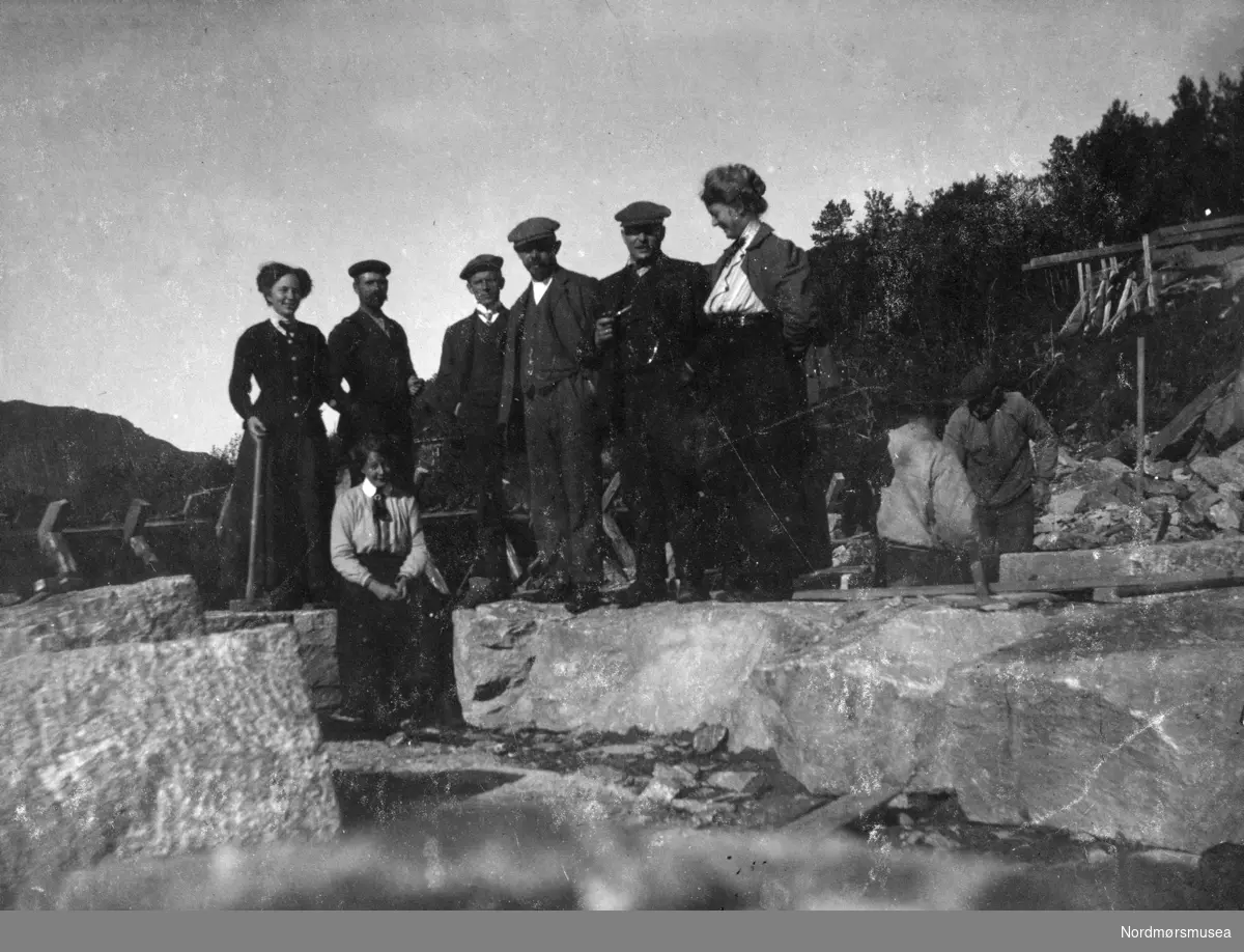 Foto av en gruppe menn og kvinner, her trolig fotografert ute på anleggsområdet ved Enge Bruk i Valsøyfjord i Halsa kommune. Samling fotografier fra Enge Bruk i Valsøyfjord i Halsa kommune. Eier av originalmaterialet er Kolbjørn Botten. Fra Nordmøre museums fotosamlinger.