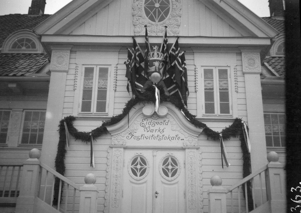 Eidsvold Værks festivitetslokale, fasade pyntet med norske flagg, girlander, granbar, grunnloven 100 år 1914.