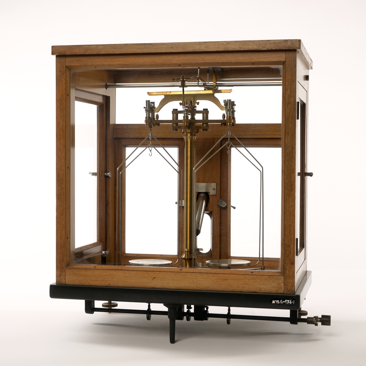 Vekt montert inn i et  monter med to dører i front og en dør på hver side. Monteret har et  "skjellet" i tre  og hvor alle sider og tak er innglasset. I fronten  er det også montert et mikroskop. På venstre side er det festet en justeringssveiv.
Under på baksiden er det skrudd fast en fot, på forsiden er det festet to justerbare føtter. Inne i monteret er det et løst speil. Alle dører har en lukkemekanisme i metall. Gulvet er antatt sort granitt. Øverst til høyre i monteren er det montert en justeringsskrue.