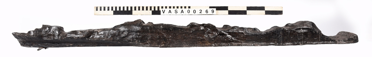 Skulpterad pilaster föreställande en herm eller möjligtvis en karyatid, under jonisk kapitäl.
Huvudet är vridet åt vänster samt prytt med en krona. Armarna hålls sträckta utefter sidorna.
Kroppen övergår i det med blad- och blomornamentik rikt sirade pilasterskaftet som smalnar av nedåt. Skaftet avgränsas genom en enkel vulst eller list från den rikt sirade och mjukt utbuktande piedestalen. Nedtill är piedestalen försedd med en bred bas. Skulpturens baksidan är slät.
Skulpturen är sliten.

Text in English: Sculptered pilaster with a Herm, or possibly a Caryatid, beneath an Ionic capital.
The head, with a crown, is turned to the left. The arms are streched out along the sides.
The body extends into the shaft of the pilaster, which tapers downwards and is richly decorated with leaf and flower ornamentation. A simple torus or batten separates the shaft from the richly decorated, softly bulging pedestal that has a broad base. The back of the sculpture is smooth.
The sculpture is worn.