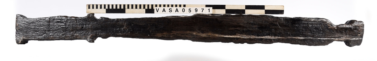 Skulpterad pilaster utformad som en karyatid med långt hår, troligen placerad under ett joniskt kapitäl.
Huvudet är vridet åt vänster. Höger arm är sträckt utefter sidan. Vänster arm är böjd och i handen håller figuren ett okänt föremål.
Pilasterskaftet är upptill prytt med en maskaron med bred, öppen mun och nedtill med en tung fruktfeston. Det nedåt avsmalnande pilasterskaftet avgränsas från piedestalen av en enkel vulst eller list med uppdragna kanter. Piedestalen är hög och jämnbred samt prydd med ett litet huvud och avslutas nedtill med en förtjockad bas. Skulpturens baksida är slät.
Skulpturen är kraftigt sliten och nött med finare detaljer utplånade.

Text in English: Sculpted pilaster with Caryatid with long hair under what is possibly an Ionic capital.
The head is turned to the left, the right arm is streched along the side, the left arm is bent and the hand holds an unknown object.
The shaft of the pilaster is decorated above with a mask with a broad, open mouth, below is a heavy festoon of fruit. The shaft tapers downwards and is divided from its pedestal by a simple torus or batten with drawn-up edges. The pedestal is high and even in width and decorated with a small head. It terminates at the bottom in a thickened base. Its back is smooth.
The sculpture is much worn, with finer details obliterated.