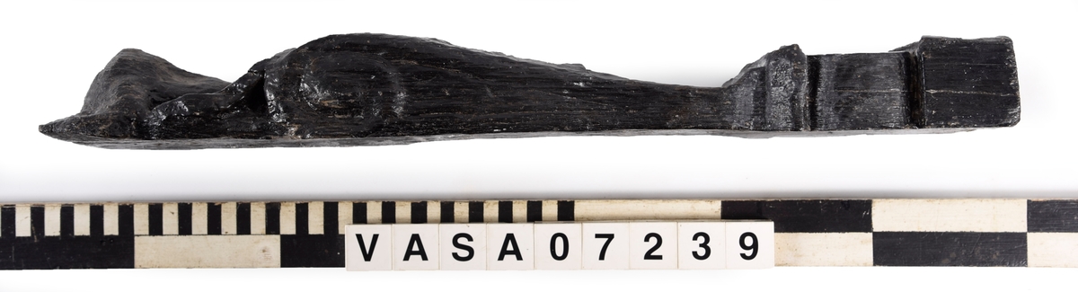 Liten skulpterad pilaster, utformad som en karyatid eller möjligen en putto. Figuren har långt hår och ett knubbigt ansikte, omgivet av en bred krage. Det nedåt avsmalnande pilasterskaftet är dekorerat med akantusblad. Nedtill avslutas pilastern av en rikt profilerad och dekorerad sockel. Skulpturens baksida är slät.
Skulpturen är sliten, främst den övre delen.

Text in English: A small carved pilaster, with a caryatid or probably a putto. The figure has a chubby face, long hair and a broad collar. The lower part of the pilaster is decorated with acanthus leaves. The caryatid stands on a richly profiled and decorated socle. The back of the sculpture is smooth.
The sculpture is worn.